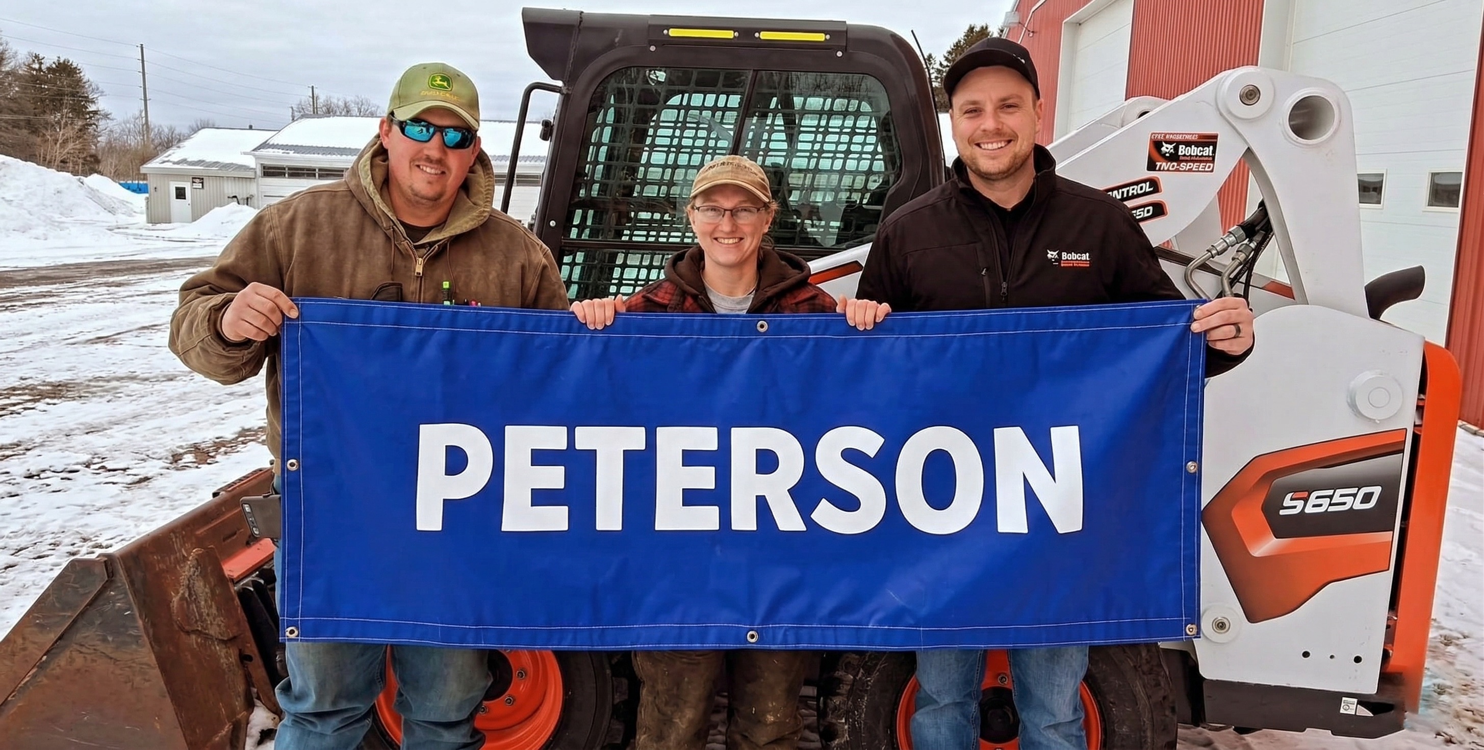 The Peterson Heavy Equipment family in front of a Bobcat S650 skid steer